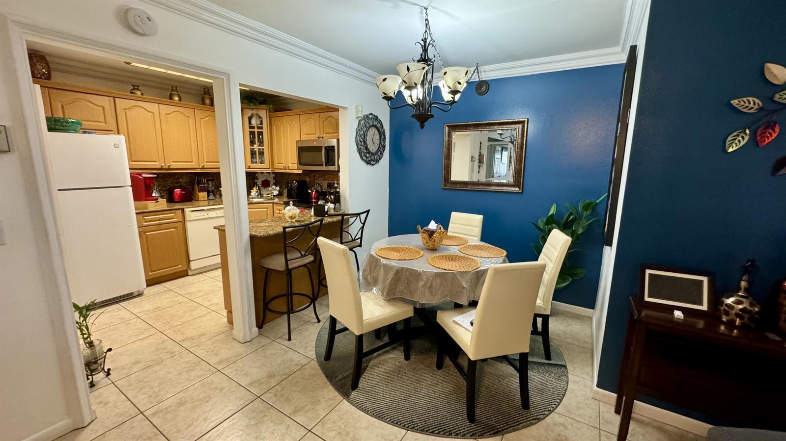 A dining area with a round table and blue accent wall opens into a kitchen — 104 Lake Pine Circle # 1, FL 33463, FL