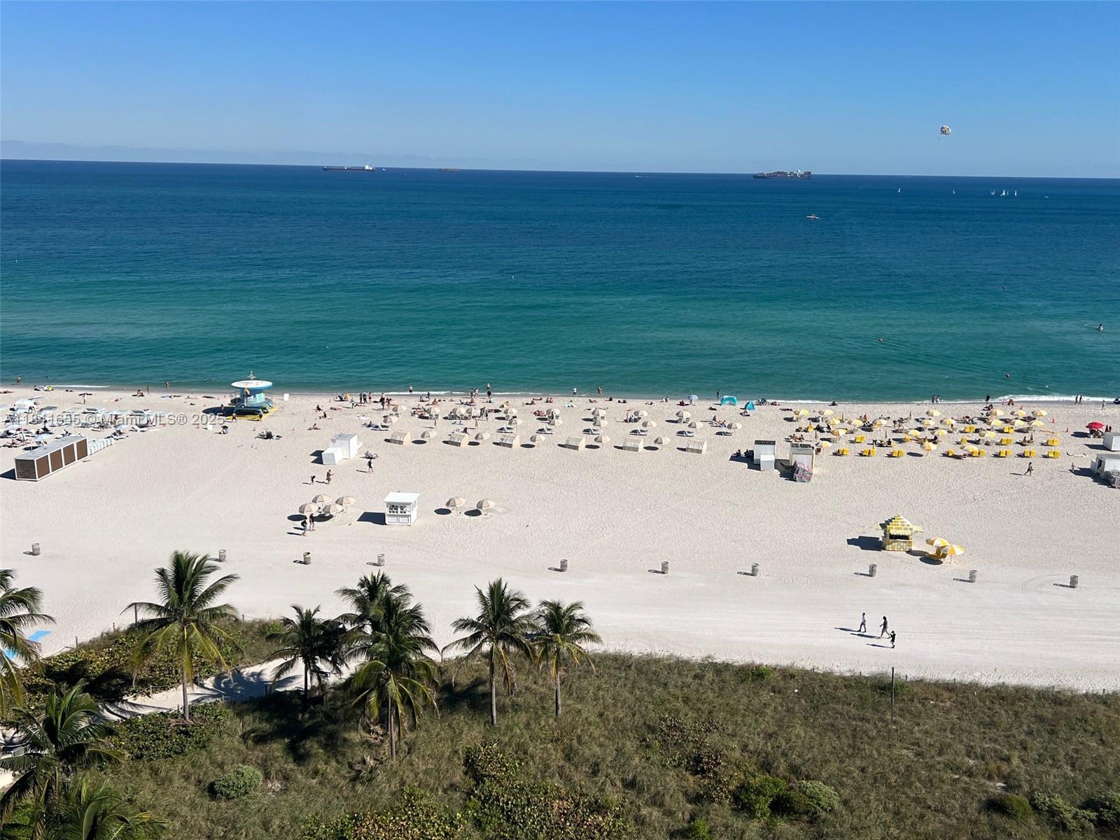 An elevated view of a sandy beach with palm trees, umbrellas, and the ocean — 100 Lincoln Rd # 1419, Miami Beach FL 33139, MIAMI BEACH, FL