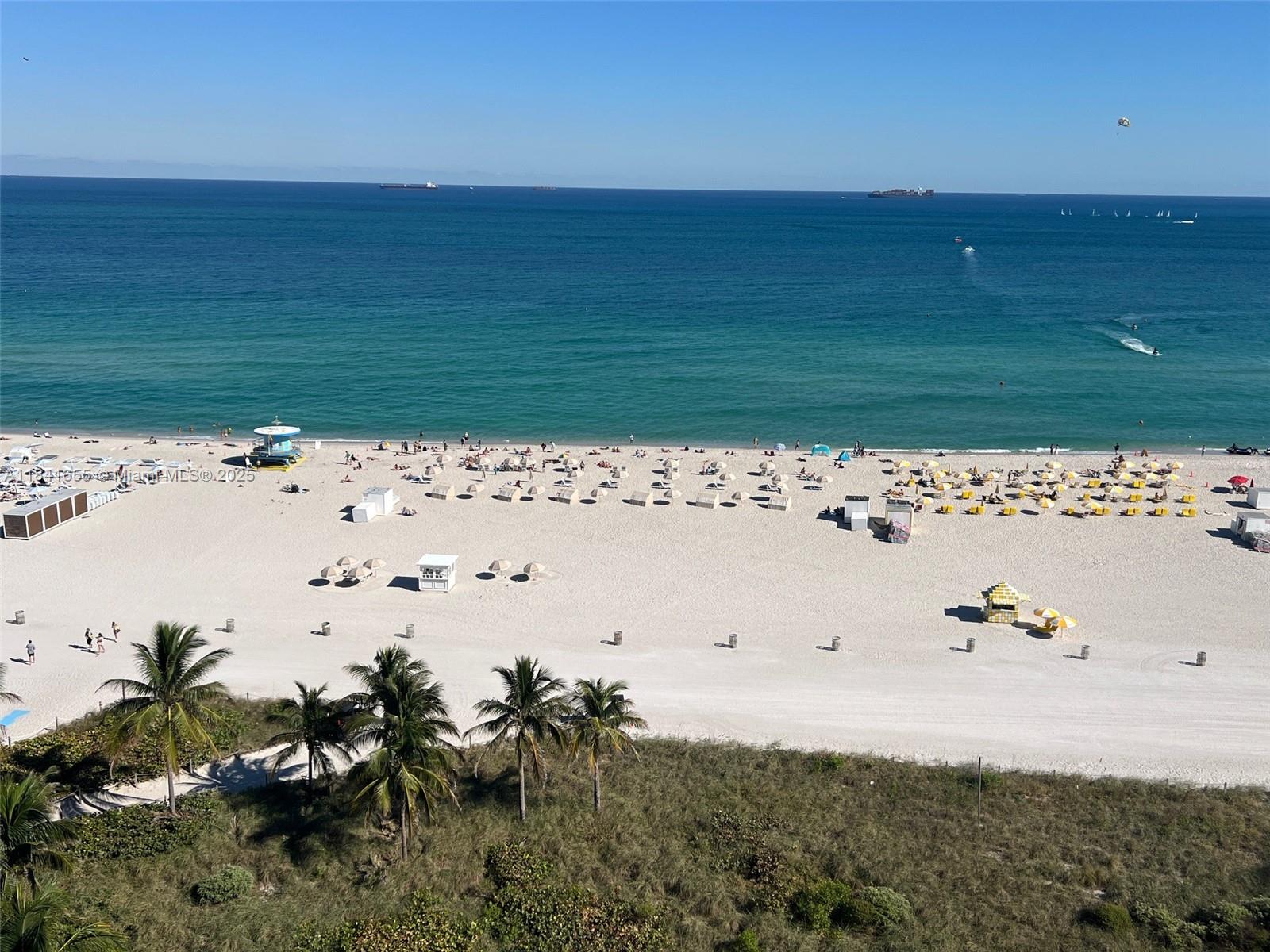 An elevated view of a sandy beach with palm trees, umbrellas, and the ocean — 100 Lincoln Rd # 1419, Miami Beach FL 33139, MIAMI BEACH, FL
