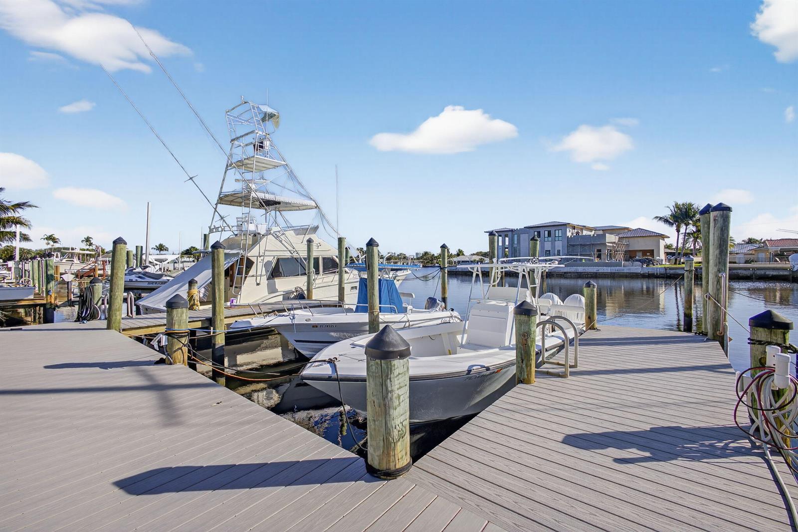 A wooden dock extends into a canal with several boats moored alongside — 752 Lagoon Drive, North Palm Beach FL 33408, NORTH PALM BEACH, FL