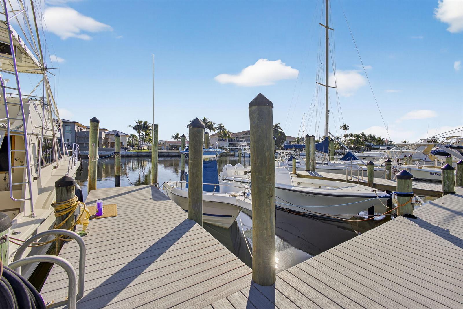 A wooden boat dock extends into a marina filled with several docked motorboats and sailboats — 752 Lagoon Drive, North Palm Beach FL 33408, NORTH PALM BEACH, FL