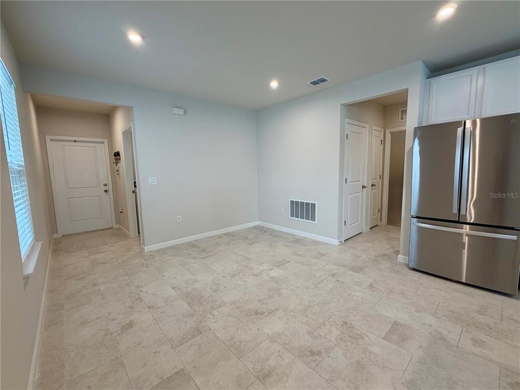 A kitchen dining area features light-colored tile flooring, white walls, and a stainless steel refrigerator — 3030 RUBY FALLS DRIVE, DELAND, FL