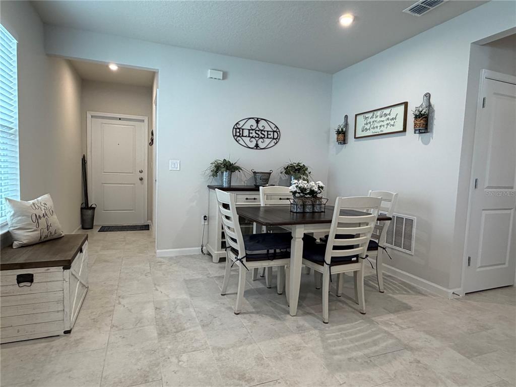 A dining area features a wooden table with four white chairs, a sideboard, and tile flooring — 3030 RUBY FALLS DRIVE, DELAND, FL