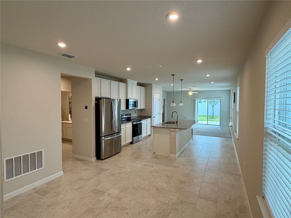 A kitchen with stainless steel appliances, a granite-topped island, and tile flooring — 3030 RUBY FALLS DRIVE, DELAND, FL