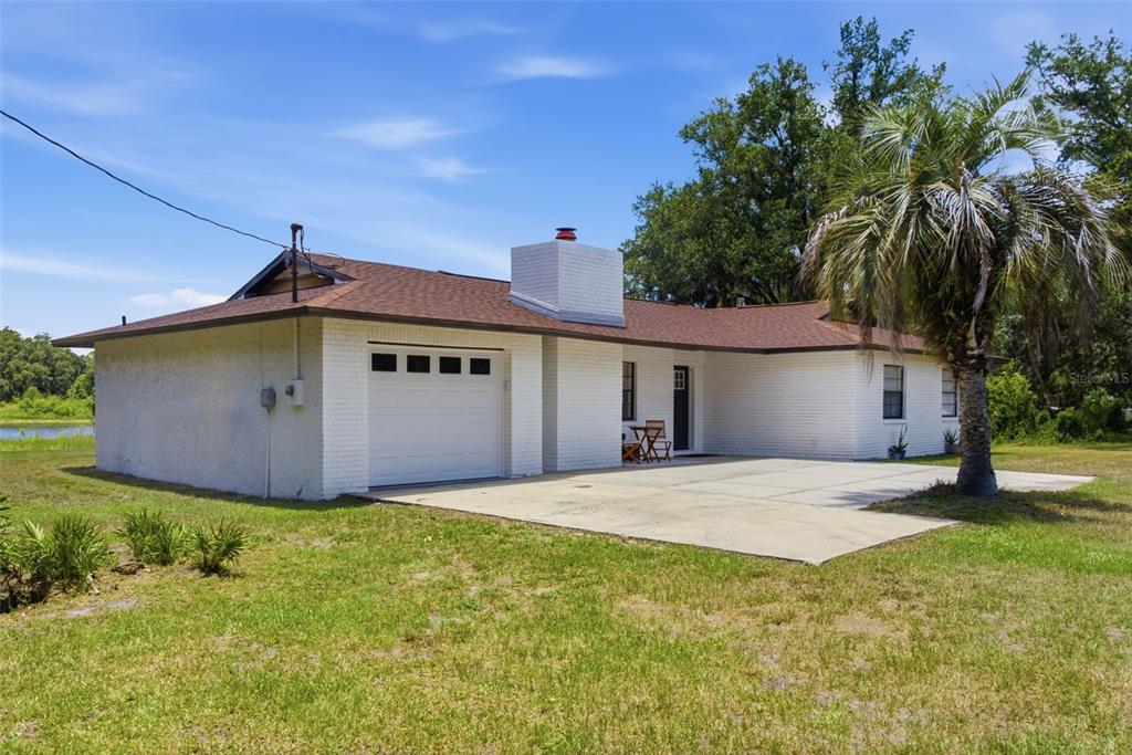 A single-story white brick house with a brown shingled roof and an attached garage — 18208 STATE ROAD 52, LAND O LAKES, FL