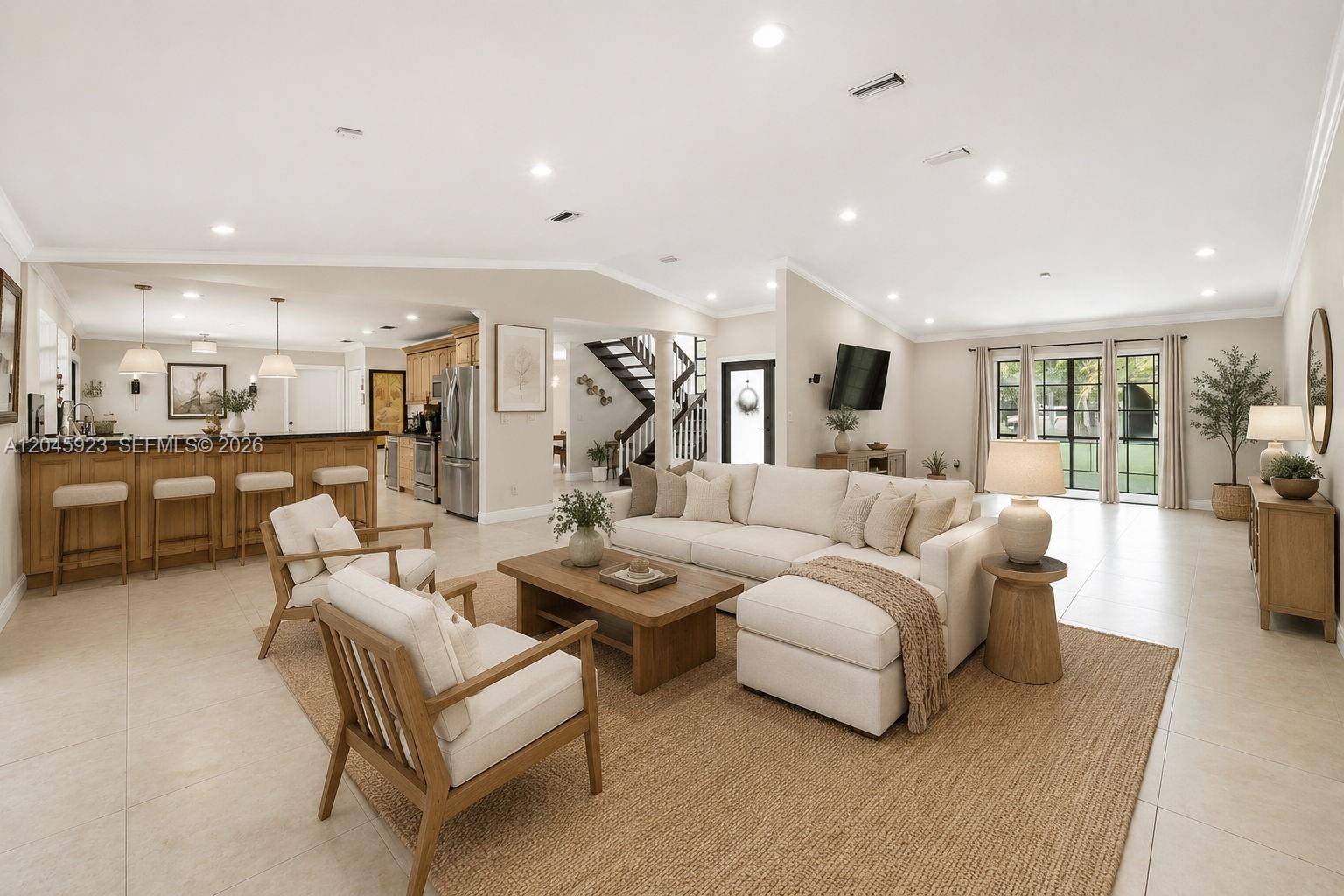 A spacious open-concept living room features a sectional sofa, wooden furniture, and a kitchen island — 16564 SW 153rd Ct, Miami FL 33187, MIAMI, FL