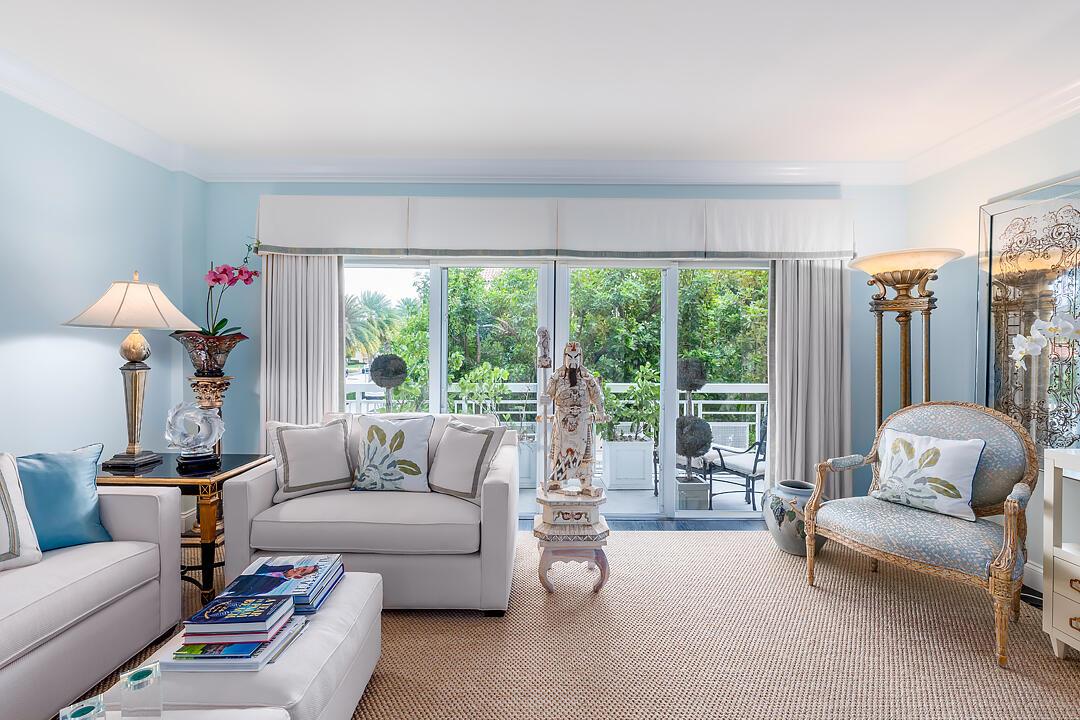 A bright living room features light blue walls, white furniture, and a balcony view — 250 Bradley Place # 202, Palm Beach FL 33480, PALM BEACH, FL