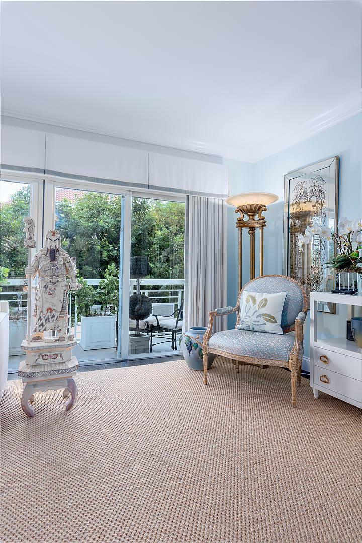 A sunlit room features a patterned armchair, a decorative warrior statue, and a sliding glass door — 250 Bradley Place # 202, Palm Beach FL 33480, PALM BEACH, FL