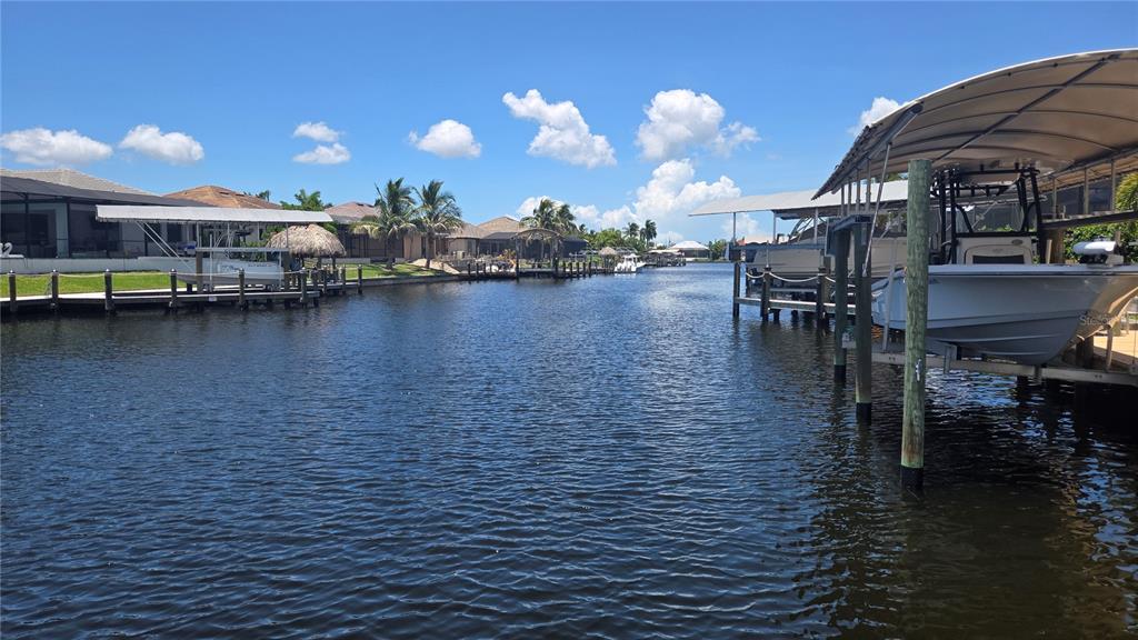 A canal view featuring boat lifts, docks, and residential homes under a blue sky — 3600 NW 2ND TERRACE, CAPE CORAL, FL