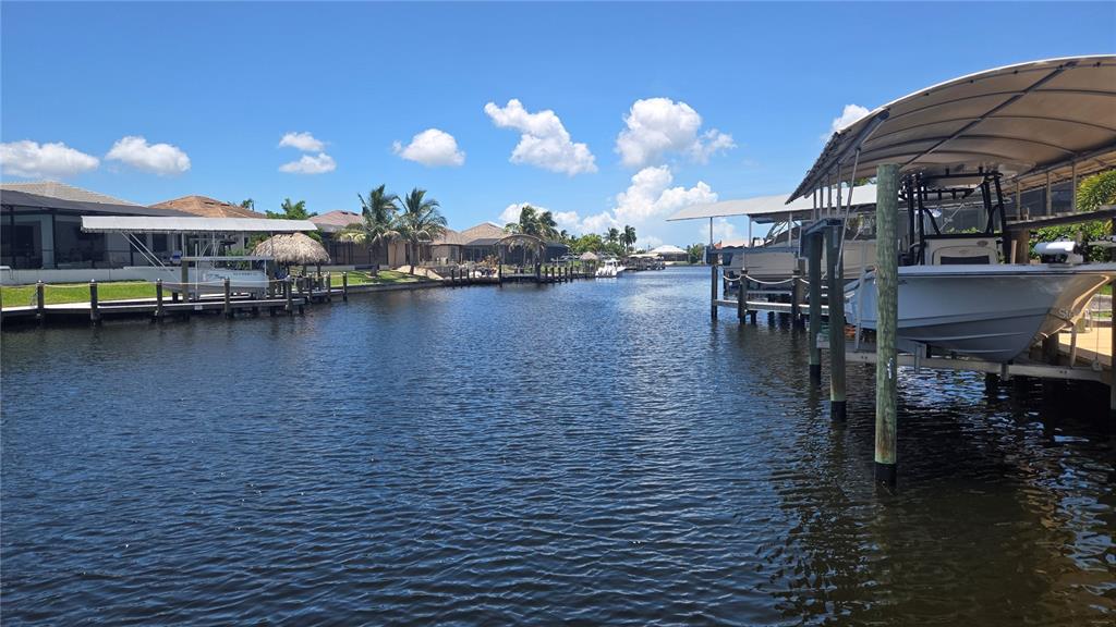 A canal view features boat lifts and docks alongside residential homes under a blue sky — 3600 NW 2ND TERRACE, CAPE CORAL, FL