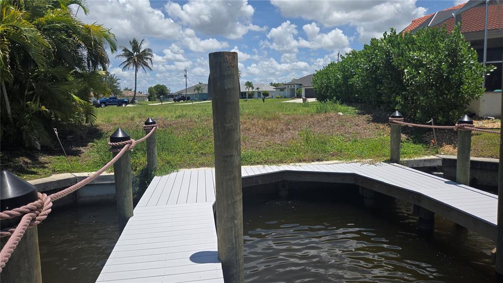 A wooden dock with gray decking extends into a canal in front of a vacant lot — 3600 NW 2ND TERRACE, CAPE CORAL, FL