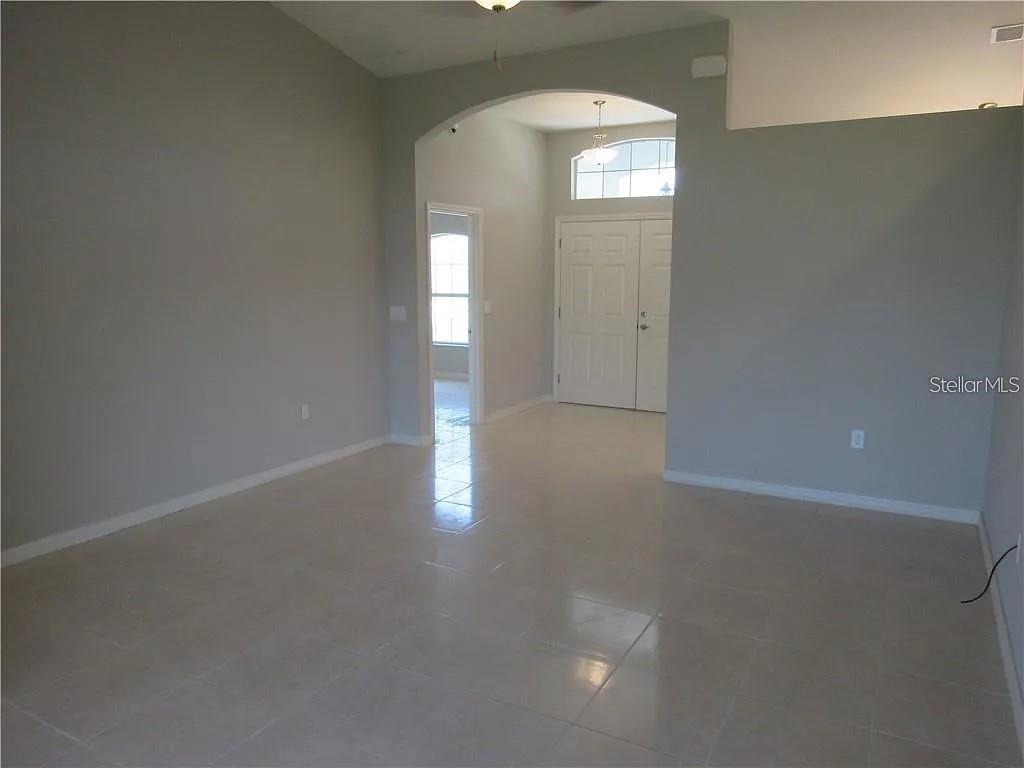 An interior view of a room with light tile flooring, gray walls, and an arched entryway — 8138 WILDER LOOP, LAKELAND, FL