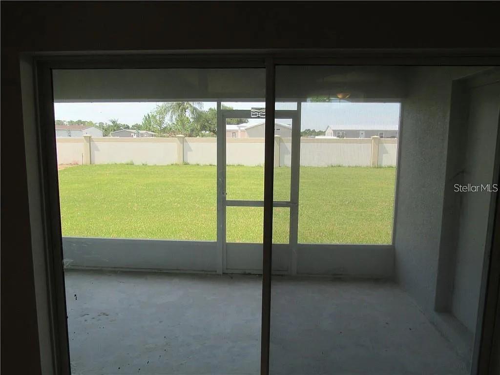 A view from inside a room looking out through a sliding door to a screened patio — 8138 WILDER LOOP, LAKELAND, FL