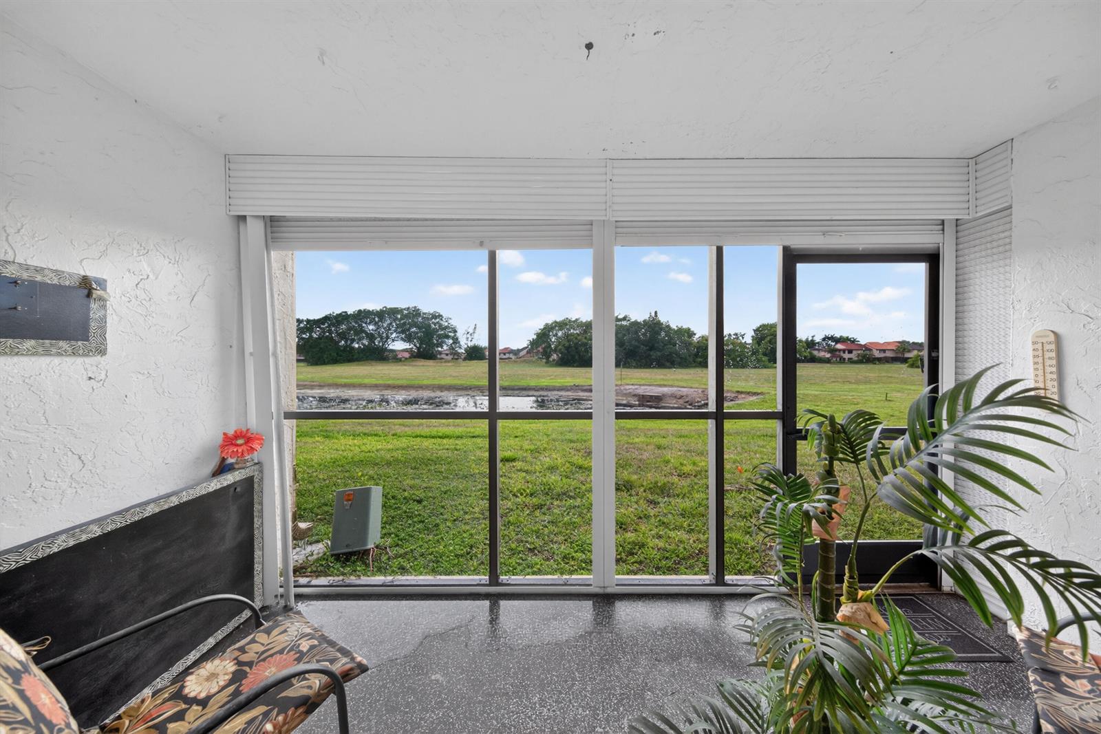 A screened-in porch with a view of a grassy field and a small pond — 3671 Environ Boulevard # 169, Lauderhill FL 33319, LAUDERHILL, FL