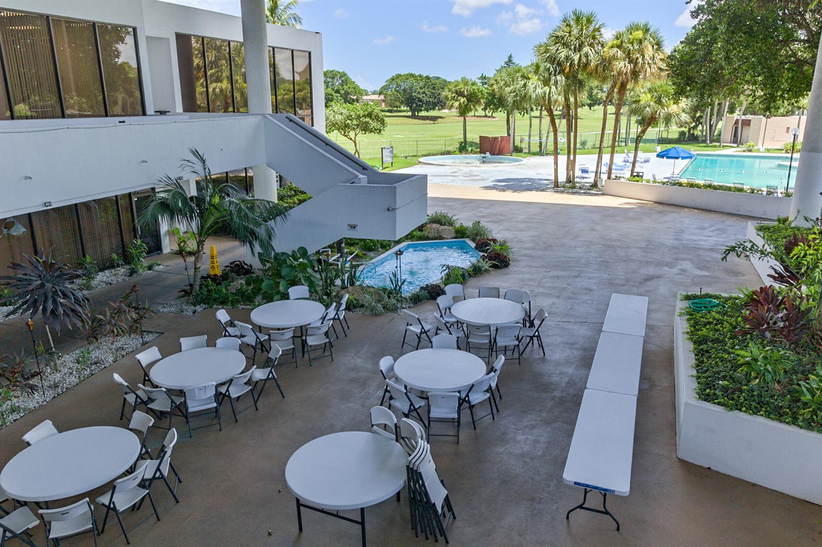 An outdoor patio area features round tables, chairs, a small fountain, and a swimming pool — 3671 Environ Boulevard # 169, Lauderhill FL 33319, LAUDERHILL, FL