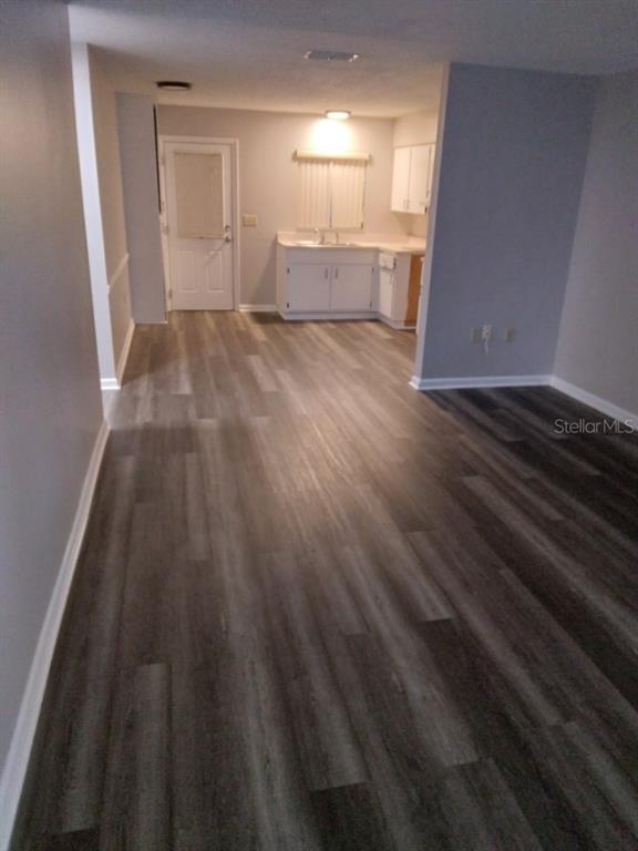 An open-concept living area features gray wood-look flooring and a kitchen with white cabinets — 27 W RAYMOND STREET, AVON PARK, FL