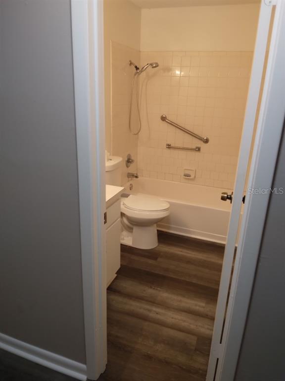 A bathroom features a white vanity, a toilet, and a tub-shower combo with grab bars — 27 W RAYMOND STREET, AVON PARK, FL