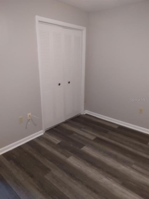 A bedroom with gray walls, wood-look flooring, and white louvered closet doors — 27 W RAYMOND STREET, AVON PARK, FL