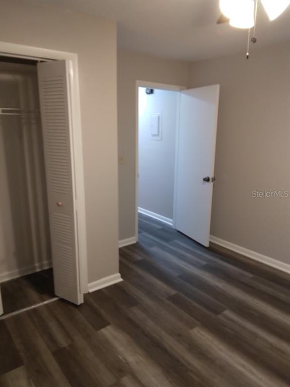 An interior room features gray wood-look flooring, a white closet door, and an open doorway — 27 W RAYMOND STREET, AVON PARK, FL