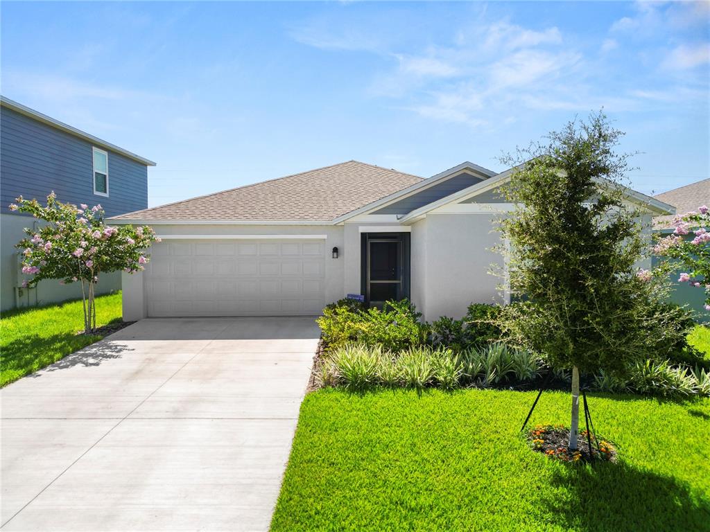 A single-story house with a light-colored exterior, a two-car garage, and a landscaped front yard — 2914 PENNACHIO DRIVE, LAKE WALES, FL