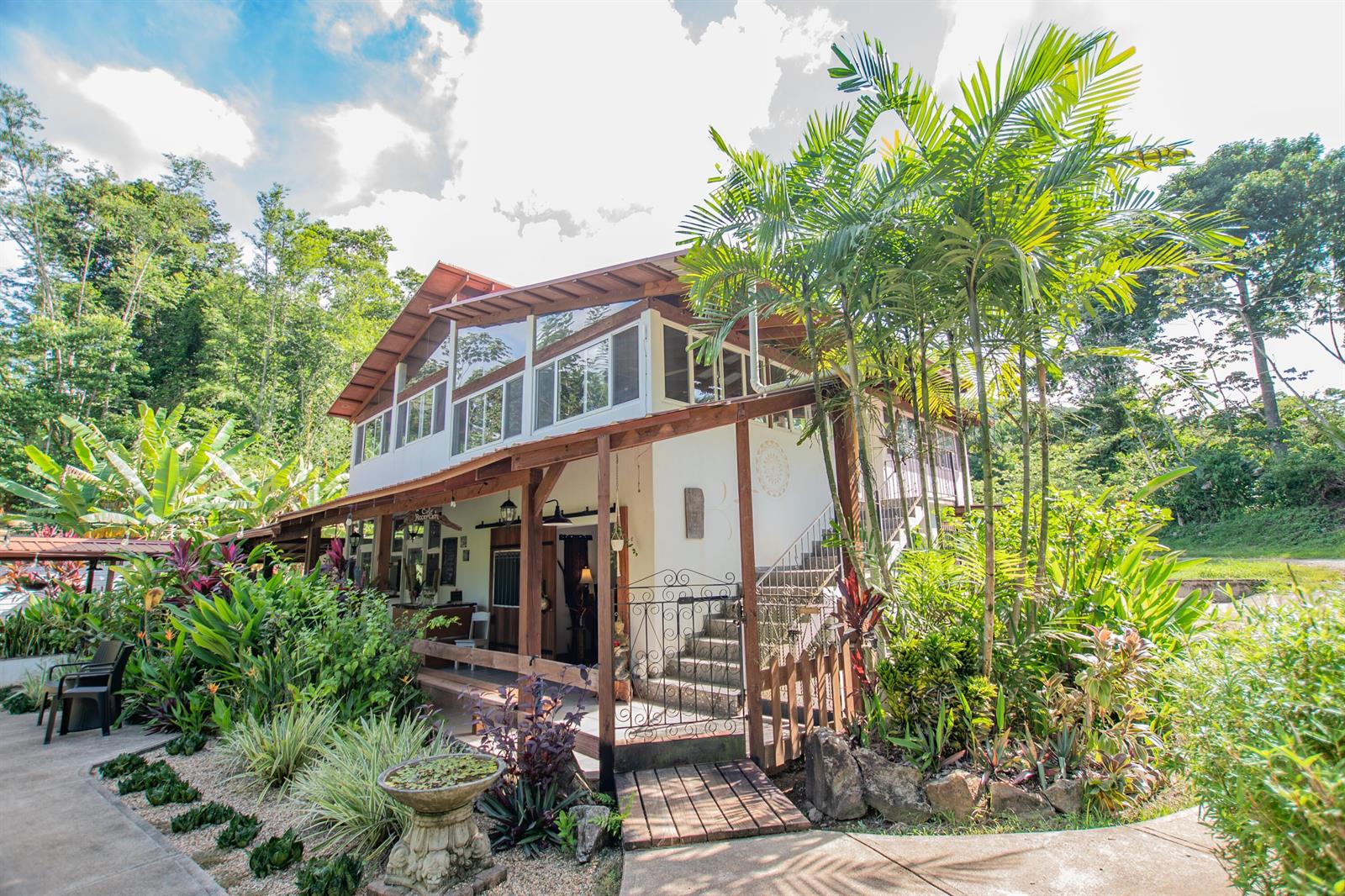 A two-story building with a wooden porch and balcony surrounded by lush tropical landscaping — 21 Hummingbird Way, 00000, FL