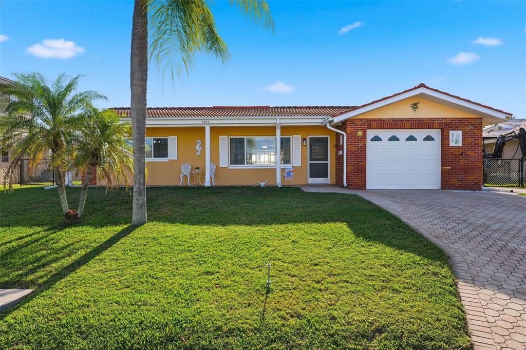 A single-story house with a yellow stucco exterior, brick accents, and a white garage door — 4926 FORECASTLE DRIVE, NEW PORT RICHEY, FL