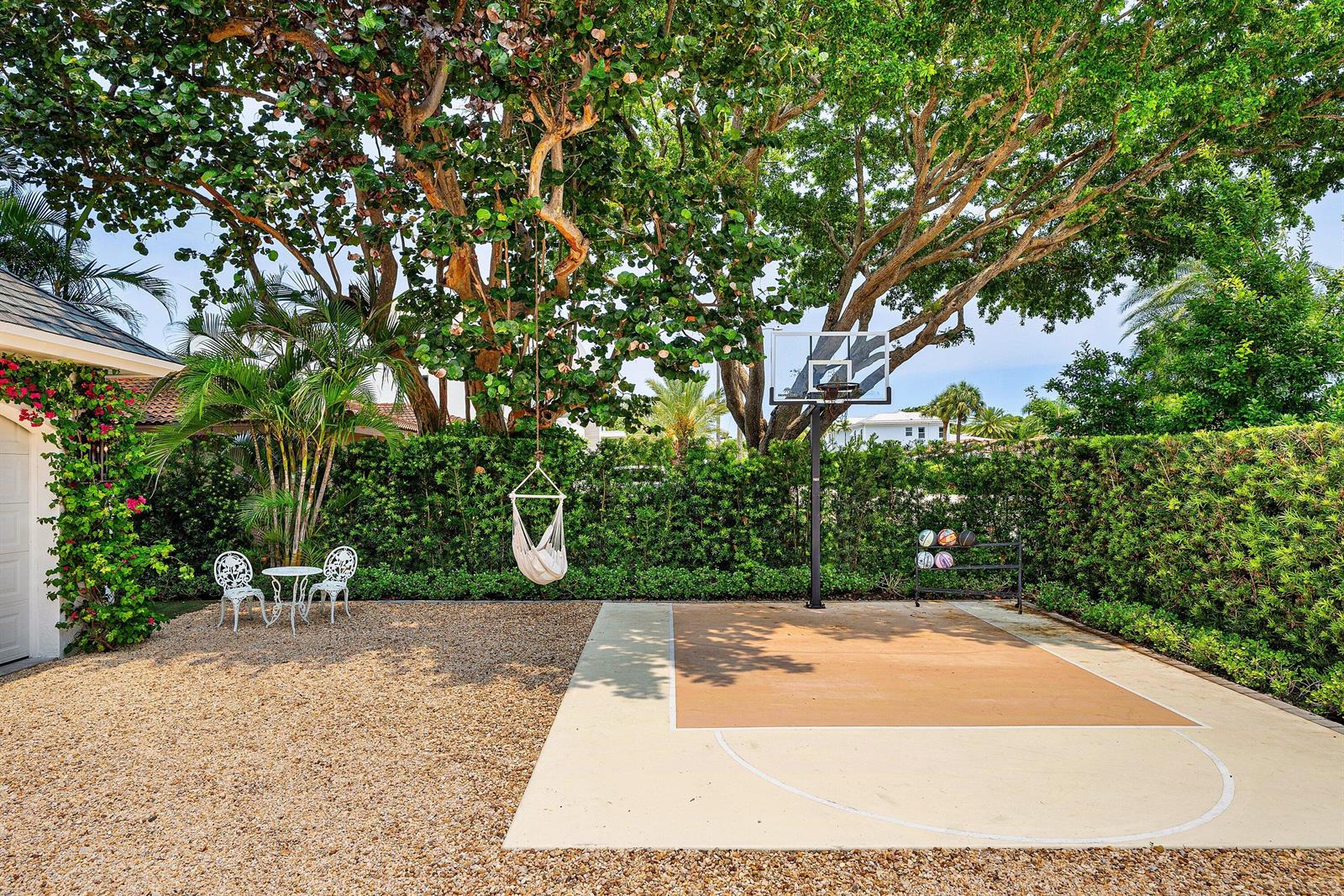 A backyard features a basketball court, a gravel area with a hanging chair, and seating — 477 NE Spanish Court, Boca Raton FL 33432, BOCA RATON, FL
