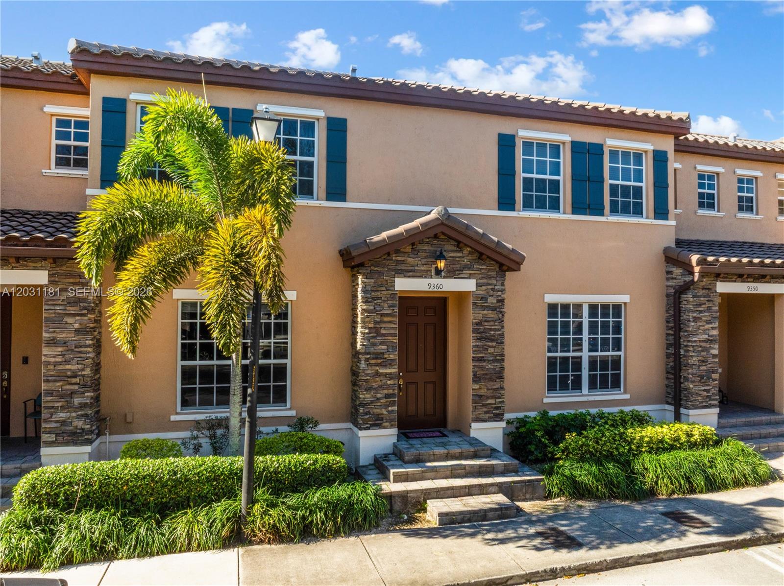 A two-story townhouse exterior with a stone-accented entryway, brown door, and a palm tree — 9360 SW 171st Ct, Miami FL 33196, MIAMI, FL