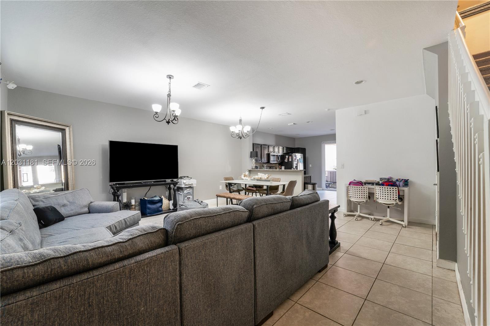An open-concept living room and kitchen area features gray tile flooring and a sectional sofa — 9360 SW 171st Ct, Miami FL 33196, MIAMI, FL