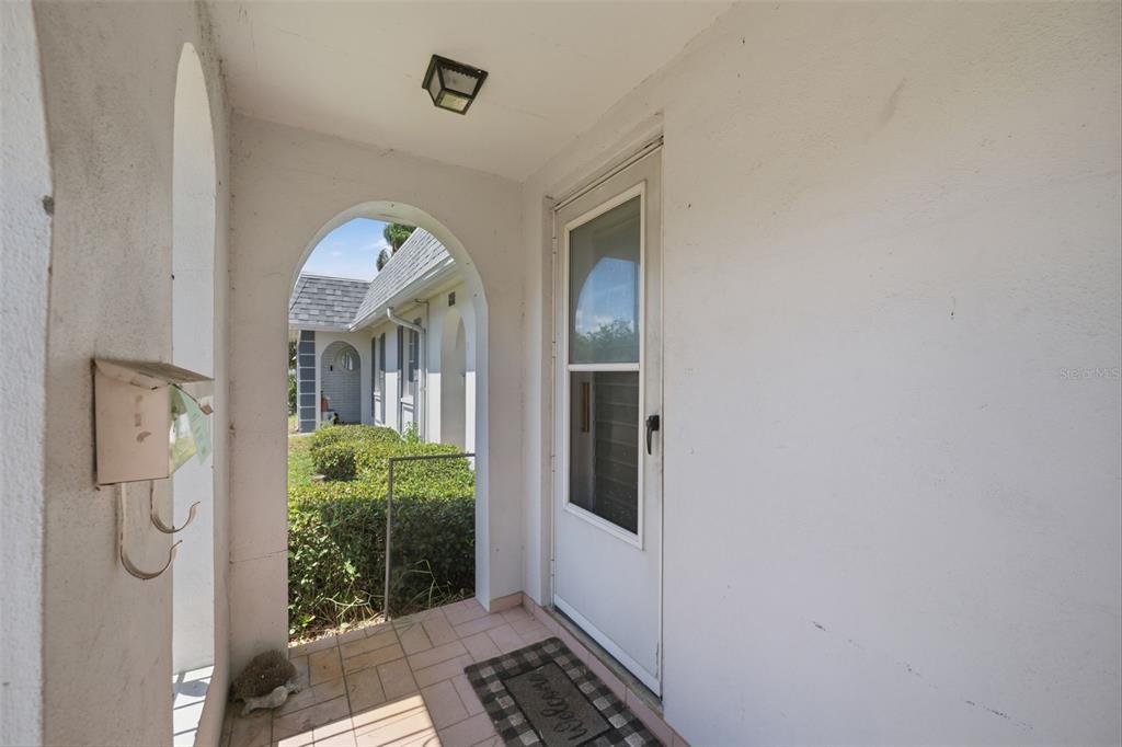 A covered entryway features a white door, a tiled floor, and an arched opening — 4209 TOUCHTON PLACE, NEW PORT RICHEY, FL