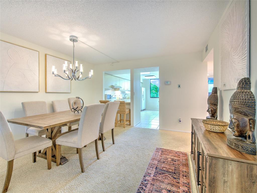 A dining room with a wooden table, upholstered chairs, a chandelier, and a side cabinet — 833 BAYPORT WAY UNIT 833, LONGBOAT KEY, FL