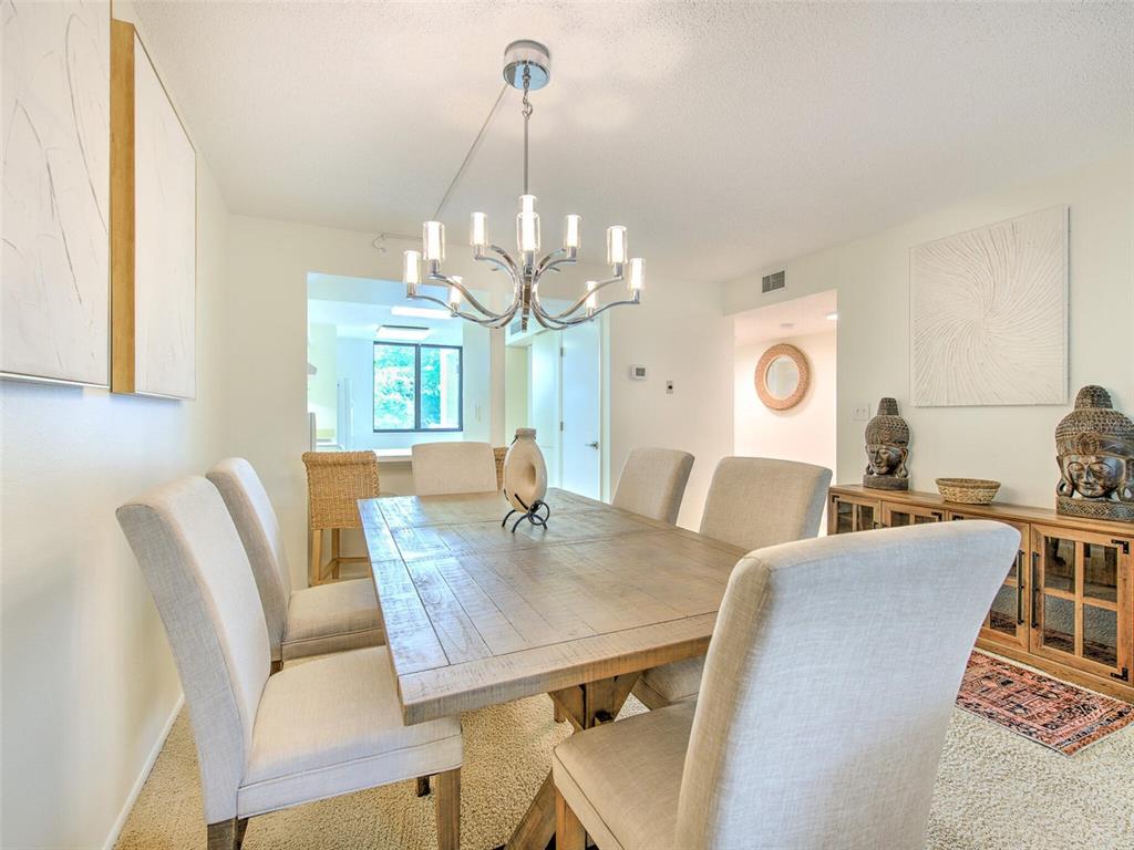 A dining room features a wooden table, upholstered chairs, a chandelier, and a side cabinet — 833 BAYPORT WAY UNIT 833, LONGBOAT KEY, FL