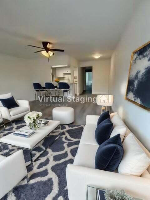 This virtual staging rendering shows a living room with white furniture and a patterned rug — 125 Westbury Circle # G, Deerfield Beach FL 33442, DEERFIELD BEACH, FL