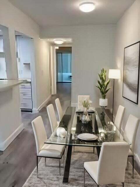 A dining room features a glass-topped table with six white chairs on a gray rug — 125 Westbury Circle # G, Deerfield Beach FL 33442, DEERFIELD BEACH, FL