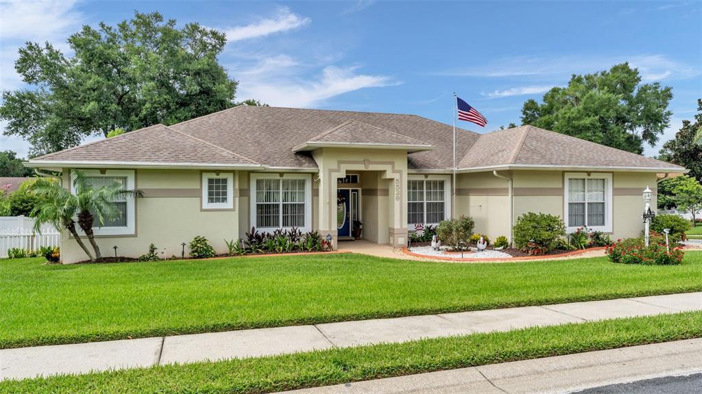 A single-story house with a light green exterior, a front lawn, and an American flag — 5539 BLOOMFIELD BOULEVARD, LAKELAND, FL