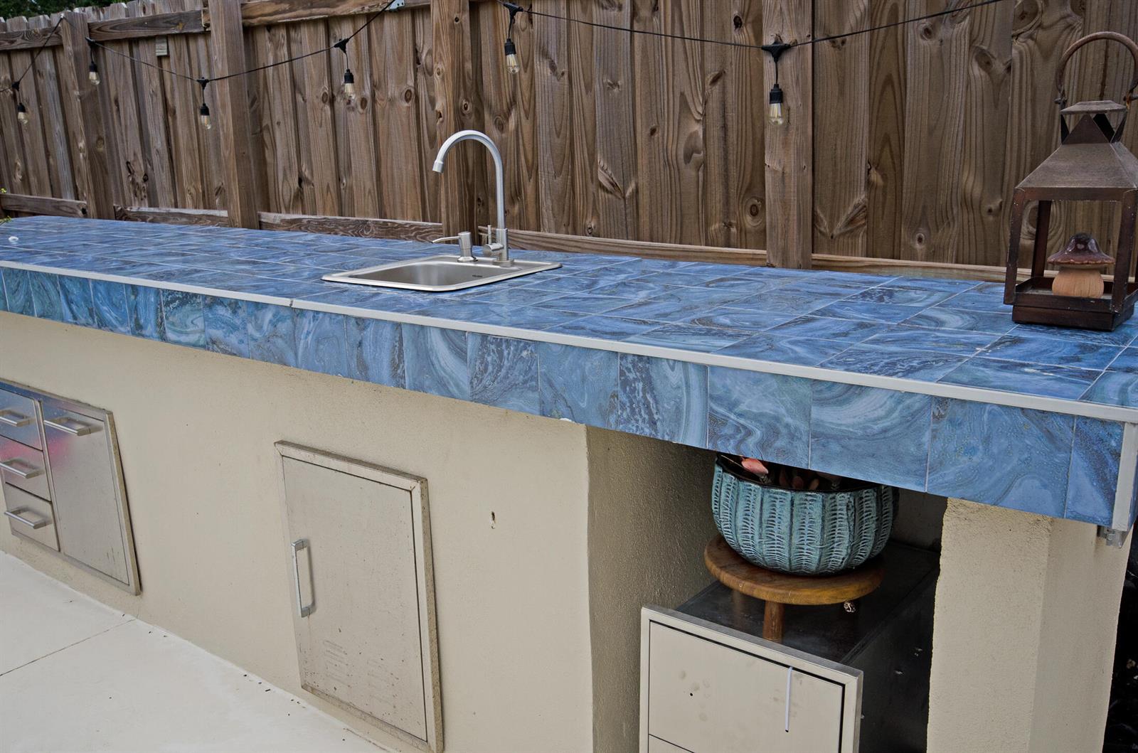 An outdoor kitchen features a blue tiled countertop, a stainless steel sink, and storage cabinets — 18324 SW 149th Place, Miami FL 33187, MIAMI, FL