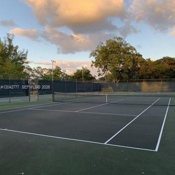 An outdoor tennis court with a net, surrounded by a chain-link fence and trees — 9495 Evergreen Pl # 102, Davie FL 33324, DAVIE, FL