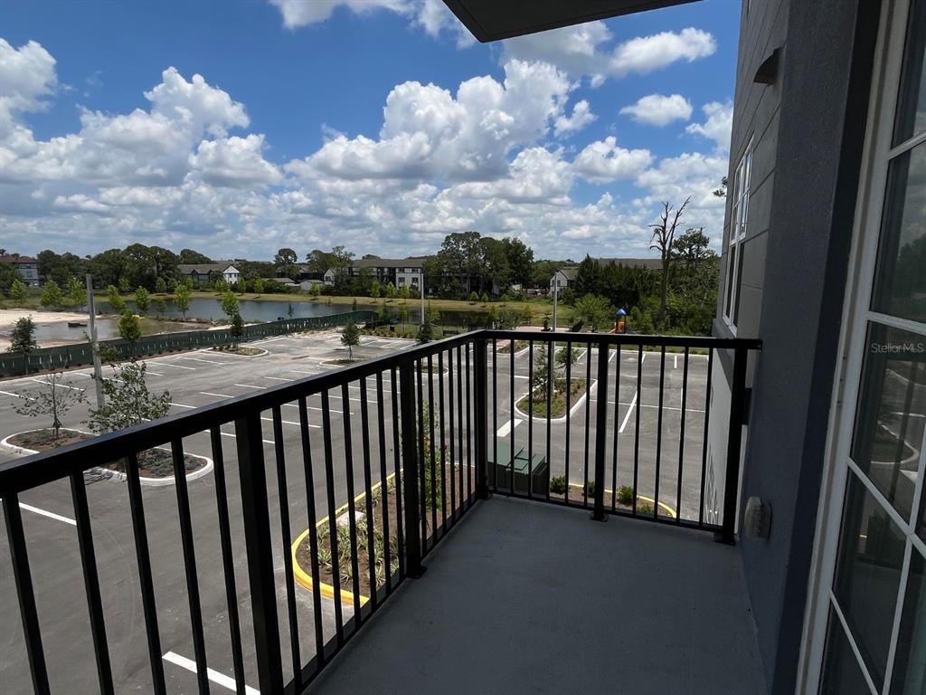 A balcony with a black metal railing overlooks a parking lot and a pond — 5579 MILLENIA PARK BOULEVARD UNIT 318, ORLANDO, FL