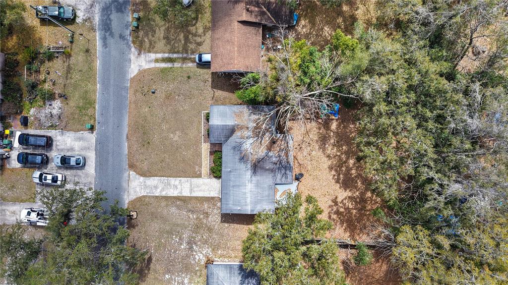An aerial view shows a house with a driveway, parked cars, and surrounding trees — 303 LOUIS STREET, LEESBURG, FL