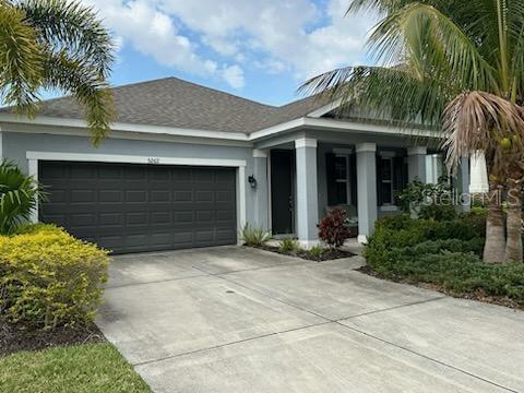 A single-story house with a gray exterior, a dark garage door, and a covered entryway — 5262 ASHER COURT, SARASOTA, FL