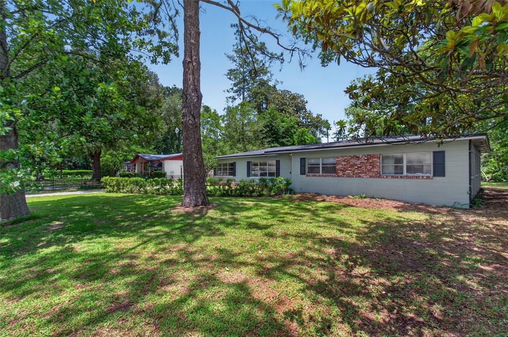A single-story house with a brick accent wall and gray siding sits on a grassy lot — 1321 NW 31ST DRIVE, GAINESVILLE, FL