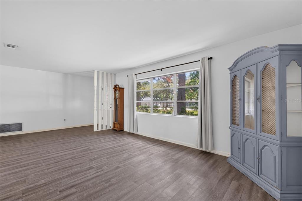 A living room with wood-look flooring, a large window, and a blue hutch — 1321 NW 31ST DRIVE, GAINESVILLE, FL