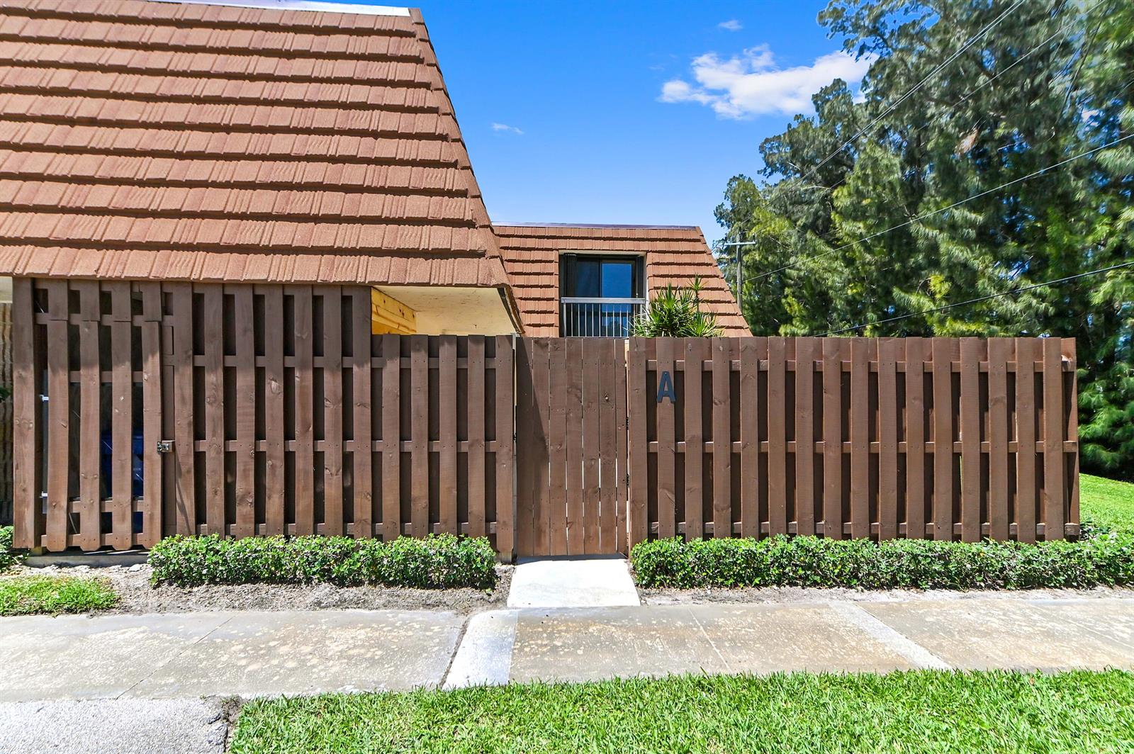 A brown wooden fence surrounds the front entrance of a home with a tiled roof — 825 Center Street # 12a, Jupiter FL 33458, JUPITER, FL