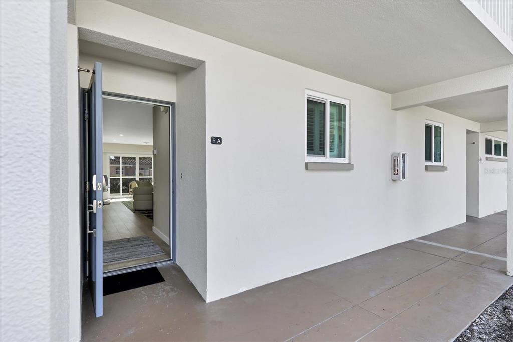 An open front door reveals a view into a bright, tiled interior living space — 500 S WASHINGTON DRIVE UNIT 5A, SARASOTA, FL