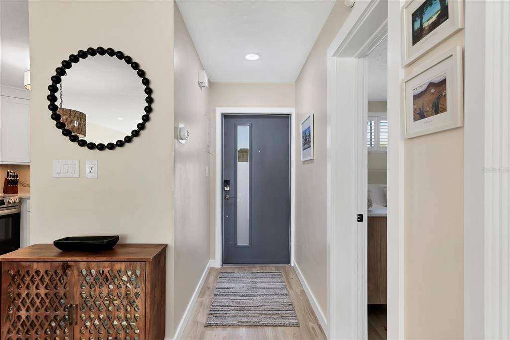 A modern entryway features a gray front door, a wooden cabinet, and a round mirror — 500 S WASHINGTON DRIVE UNIT 5A, SARASOTA, FL
