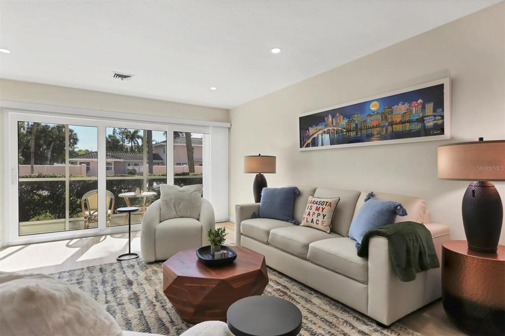 A living room features a beige sofa, a wood coffee table, and sliding glass doors — 500 S WASHINGTON DRIVE UNIT 5A, SARASOTA, FL