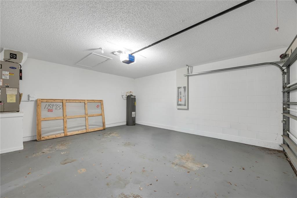 An empty garage with a concrete floor, white block walls, a water heater, and HVAC unit — 2980 BEAL ST STREET, DELTONA, FL
