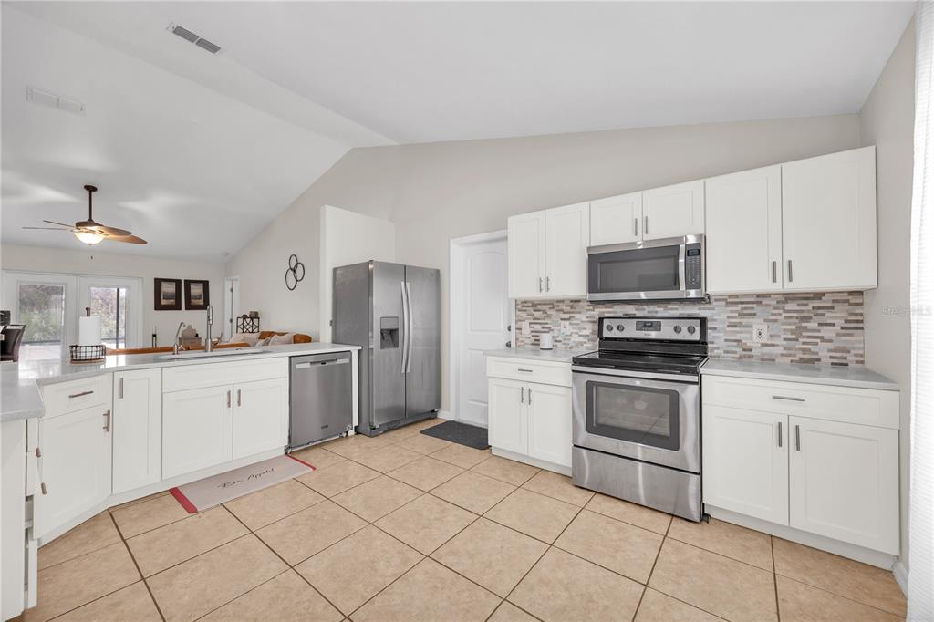 A kitchen with white cabinets, stainless steel appliances, and tan tile flooring — 2980 BEAL ST STREET, DELTONA, FL