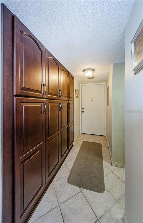 A hallway features dark wood cabinetry, light tile flooring, and a white door at the end — 90 S HIGHLAND AVENUE UNIT 214, TARPON SPRINGS, FL