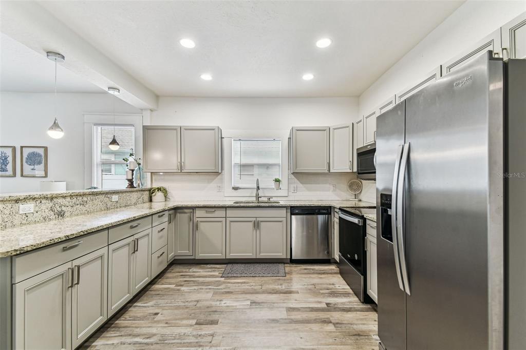 A kitchen features light gray cabinets, granite countertops, stainless steel appliances, and wood-look flooring — 904 E HAMILTON AVENUE, TAMPA, FL